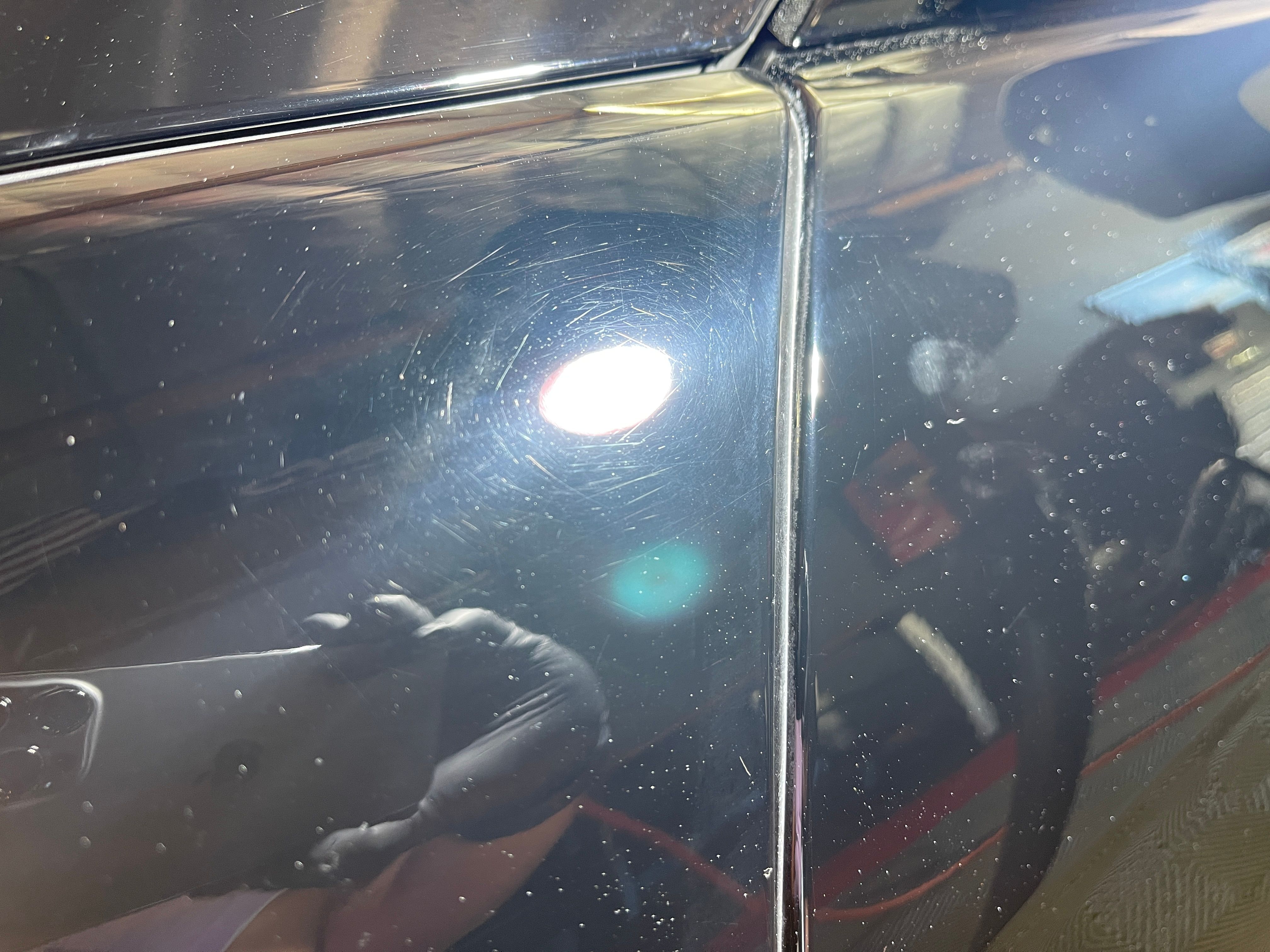 Severe scratches and swirl marks covering the black paint of a Mercedes SL550 before restoration work began