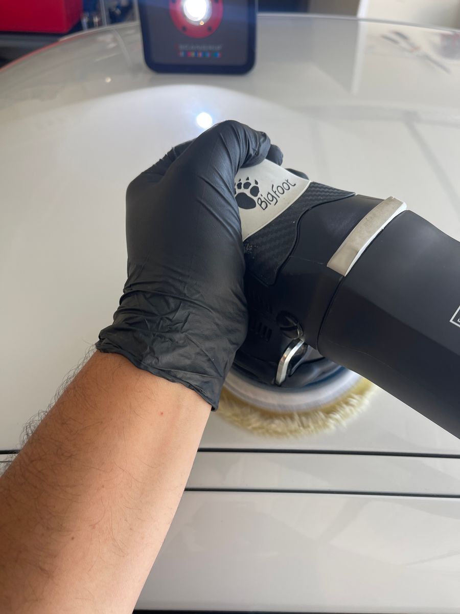 Professional paint correction in progress using machine polisher and inspection lighting