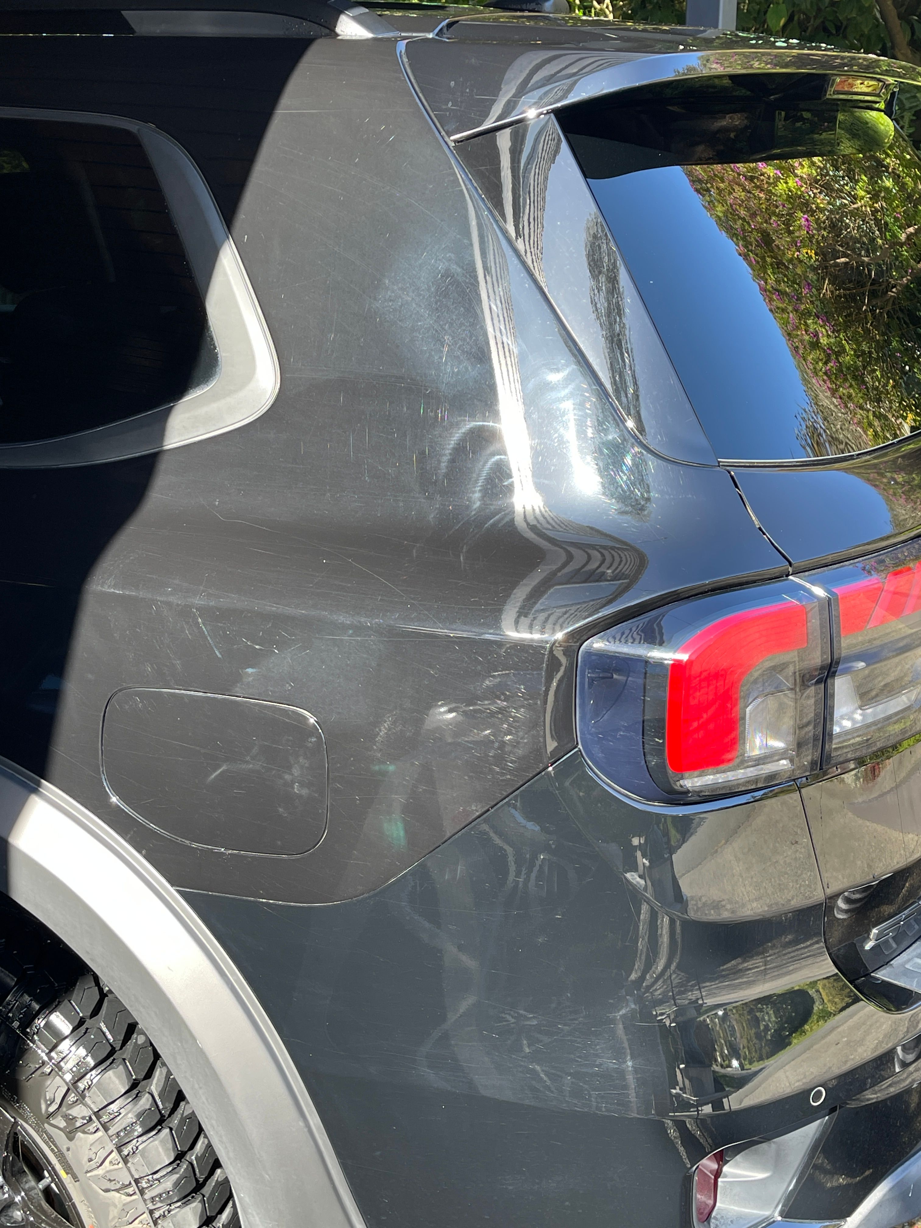 Black vehicle showing mix of incorrect cleaning damage and professional buffing holograms especially evident above tail lights