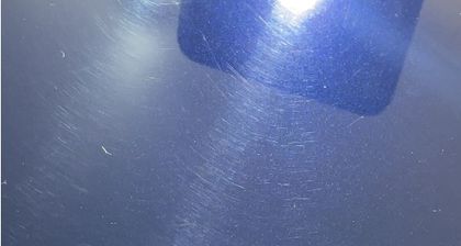 Fine circular swirl marks visible across dark paintwork in direct light
