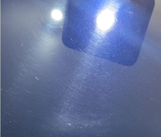 Swirl marks on vehicle paint visible under specialized lighting revealing extensive damage invisible in normal conditions